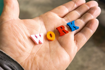 Multi-colored letters word work on a man's hand.