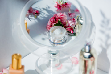 Perfume bottle, skin care cream and dianthus flowers