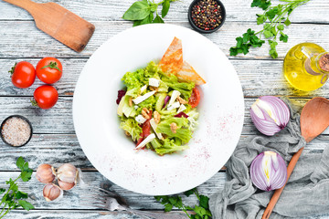 Vegetable salad with cheese, olives and cherry tomatoes. In the plate. Top view. Free space for your text. Rustic style.