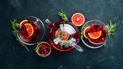 Hot tea with berry cranberry and orange. On the black kitchen background. Top view. Free space for...