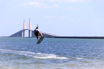 Kite surfer gaining air with a kite above as he attempts to jump the skyway bridge,