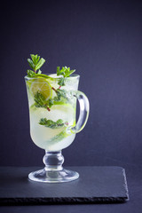 Mojito on black background. Mojito cocktail with lime and fresh mint on slate board. Summer refreshing cocktail with citrus on dark background. Copy space
