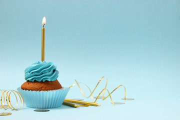  Delicious cupcake with a candle on a colored background with space to insert text. Festive...