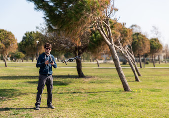 A man piloting a drone in the park in spring-summer time