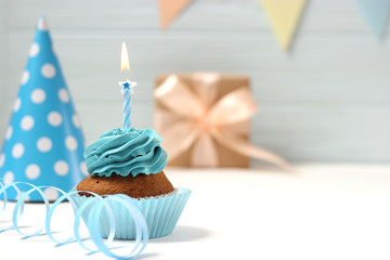  Delicious cupcake with a candle on a colored background with space to insert text. Festive background, birthday.