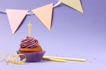  Delicious cupcake with a candle on a colored background with space to insert text. Festive...
