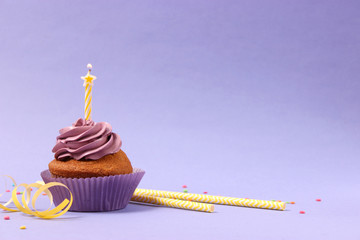  Delicious cupcake with a candle on a colored background with space to insert text. Festive...