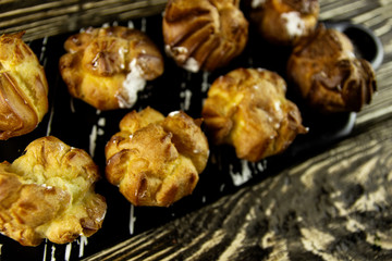 Small eclairs with cream on a wooden background
