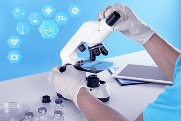 Informational icons and doctor using microscope at table, closeup. Medical investigation