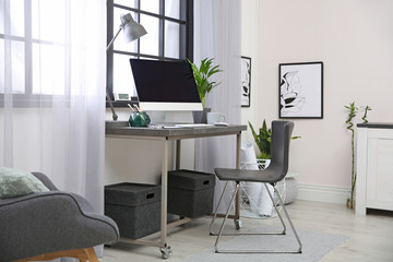 Stylish workplace with computer near window at home office. Space for text