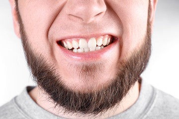 Fototapeta premium Young man with healthy teeth smiling on white background, closeup