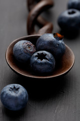 A wooden spoon with fresh bluberries, on a distressed grey wooden background