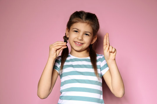 Little girl using sign language on color background
