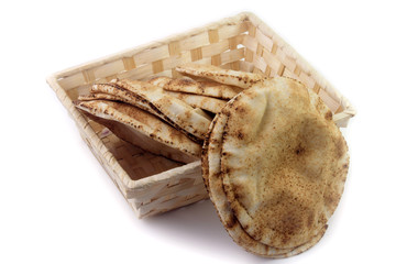 Pita bread isolated on white background in the breakfast basket. Traditional food of Arabic cuisine