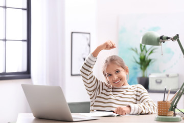 Pretty preteen girl doing homework at table in room