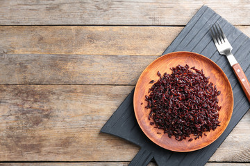 Boiled brown rice served on wooden table, top view. Space for text