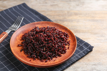 Plate of boiled brown rice and fork on table. Space for text