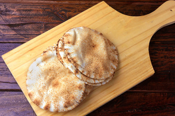 Pita bread isolated on wooden spatula coming out of the oven. Traditional food of Arabic cuisine