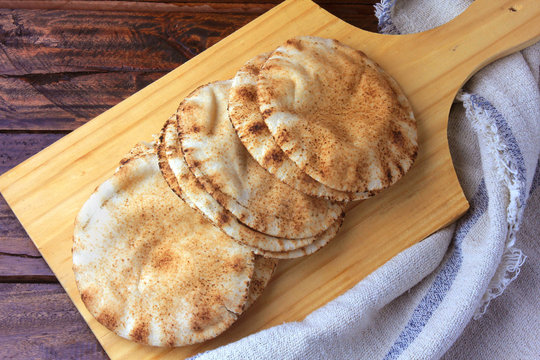 Pita Bread Isolated On Wooden Spatula Coming Out Of The Oven. Traditional Food Of Arabic Cuisine