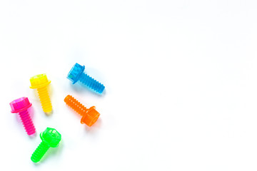 Colored translucent toy bolts on white background. Flat lay. Concept World Dad's Day, unisex toys for early development, role-playing games. Layout for social media, toy stores. Copy space.