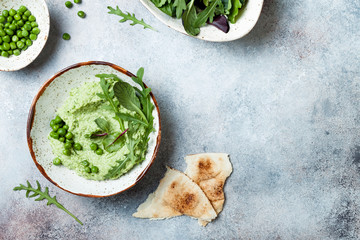 Green pea hummus spread or dip with mix salad leaves. Healthy raw summer appetizer, vegan,...