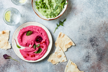Green pea and pink beet hummus spread or dip with mix salad leaves. Healthy raw summer appetizer,...