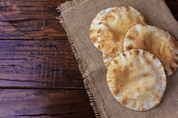 Pita bread isolated on rustic wooden table on rustic cloth. Traditional food of Arabic cuisine