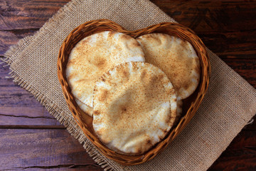 Pita bread isolated on white background in the breakfast basket, on rustic wooden table.Traditional...