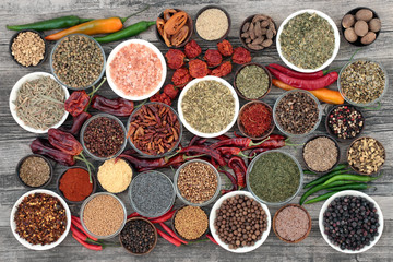 Herb and spice food selection dried and fresh on rustic wood background. With dried ring of fire, padron and scorpio chilli peppers. Top view.