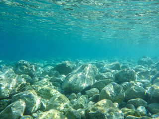 Fototapeta na wymiar UNDERWATER view of turquoise clear water and white pebbles scattered off the seabed of the Antisamos bay, Kefalonia island, Ionian Sea, Greece.