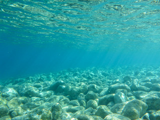 Naklejka na ściany i meble UNDERWATER view of turquoise clear water and white pebbles scattered off the seabed of the Antisamos bay, Kefalonia island, Ionian Sea, Greece.