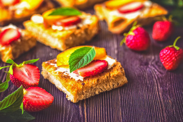 crunchy croutons with soft cheese and fresh strawberries. lunch of berry sandwiches. sandwiches with strawberries and mint leaves close-up.