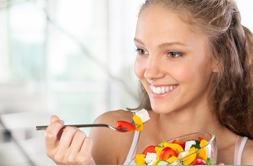 Young woman eating fruits from glass on blurred background