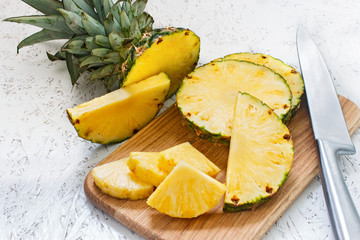 Sliced pineapple on a wooden board on a white background. Pineapple pieces of various sizes