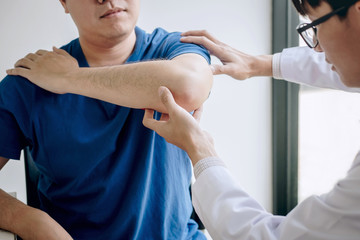 Obraz premium Doctor physiotherapist assisting a male patient while giving exercising treatment massaging the arm of patient in a physio room, rehabilitation physiotherapy concept