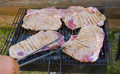 Beefs and steaks on barbecue grill fire, smoke. Spicy marinated raw lamb / calf meat beef, many...