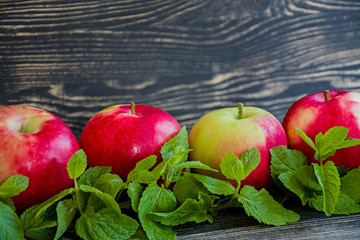 Ripe red apples with mint. Side view. Space for text. Dark wooden background.