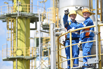Arbeiter in der Industrie in einer Raffinerie - Teamwork // teamwork: group of industrial workers in a refinery - oil processing equipment and machinery