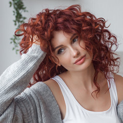 Very attractive young woman indoors. Portrait of curly haired female. Redhaired beautiful woman at...