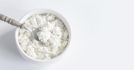 fresh cottage cheese in white Cup and spoon top view. copy space. cottage cheese on white background.