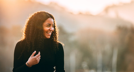 Happy attractive young African American lady looking away on blurred background