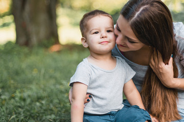 Mother with little son spend time together in green park.