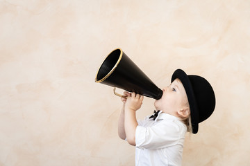 Funny child playing with black retro megaphone