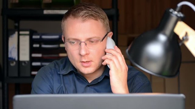 Mann sitzt am Schreibtisch und erh&auml;lt einen Anruf