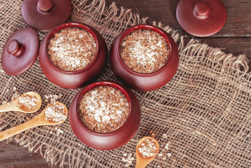 oat flakes in ceramic pots and wooden spoons close-up. oat flakes in pots for baking top view. cooking oatmeal in the kitchen.