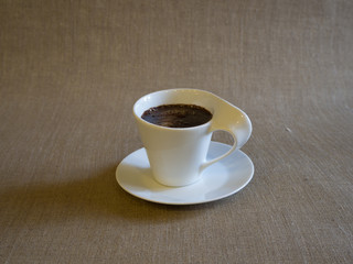 White cup of coffee on the grey tablecloth