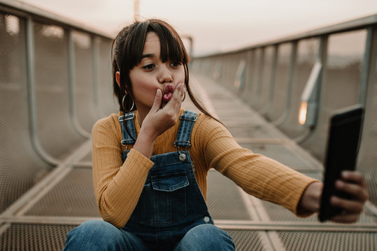 Funny girl taking selfie on smartphone on walkway