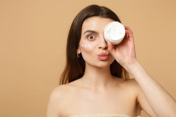 Close up half naked woman 20s with perfect skin nude make up applying facial cream isolated on...