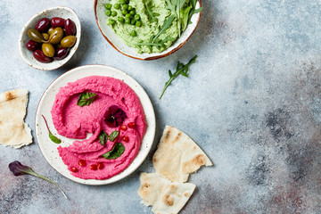Green pea and pink beet hummus spread or dip with mix salad leaves. Healthy raw summer appetizer,...