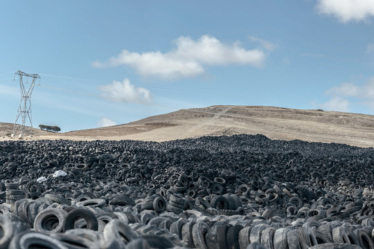 Huge pile of old auto tires between meadow